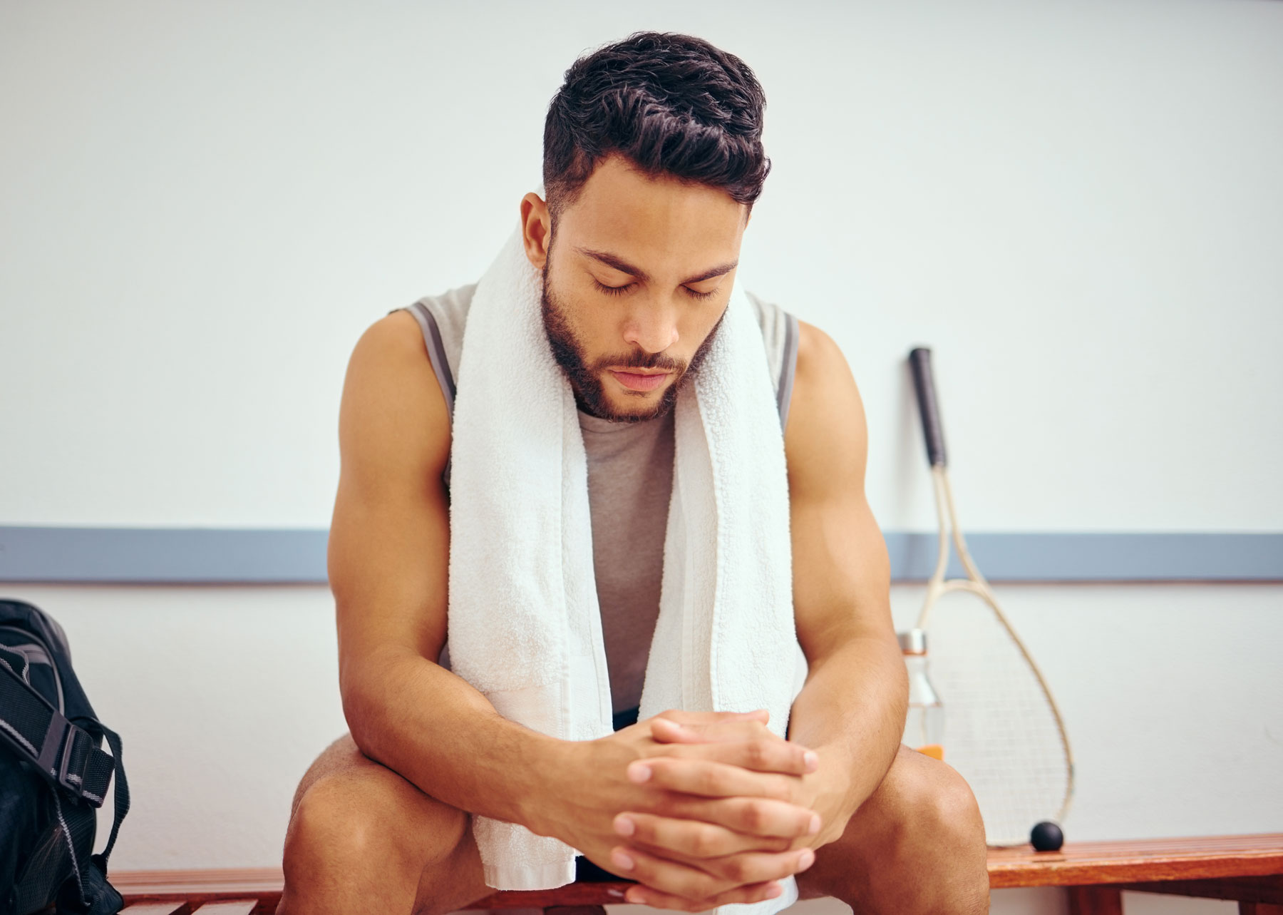 young fit man sitting on a bench with his eyes closed