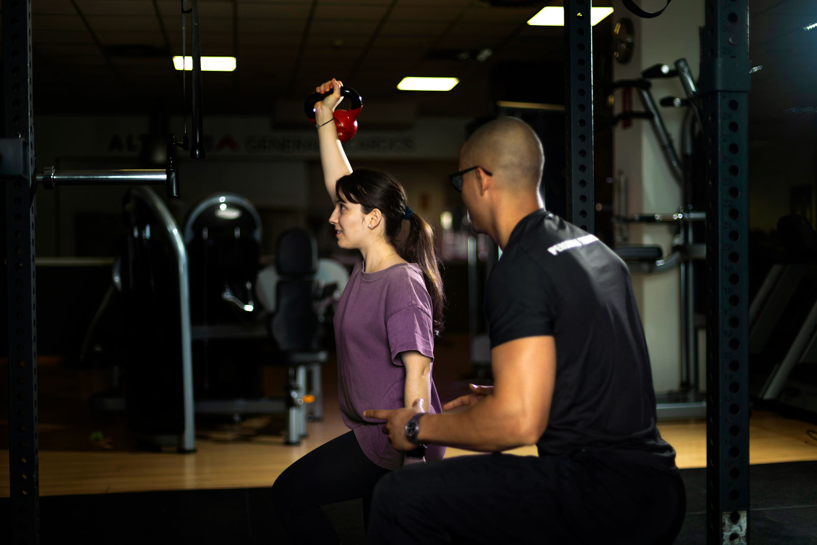 woman performing kettle bell exercise with personal trainer.